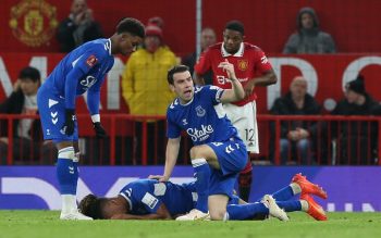 Alex Iwobi on the turf surrounded by Manchester United defender Tyrell Malacia and his teammates